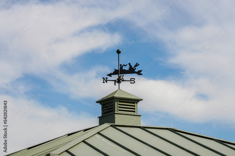 Weather vane in the form of a canoe against the blue sky. Weather vane in the form of a canoe against the blue sky.