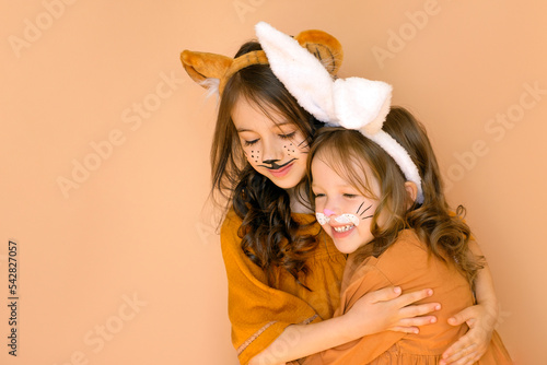 Girls in the guise of a rabbit and a tiger are symbols of the outgoing old year 2022 and the new year 2022. Children with animal makeup with hats with ears.