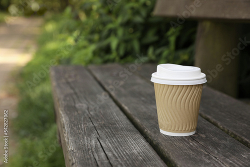 Paper cup on wooden bench outdoors, space for text. Coffee to go © New Africa
