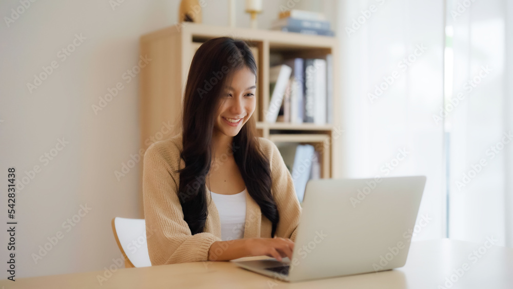 Young asian woman working at home. Female using computer laptop on desk at house Young asian woman working at home. Female using computer laptop on desk at house