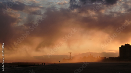 Sudden sand storm on the beach at Coney Island at Sunset with masked passerby people photo