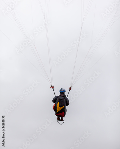 Skydiving extreme sports- parachutist with a parachute unfolded. The sportsman flying on a paraglider. Beautiful paraglider in flight on a light background.