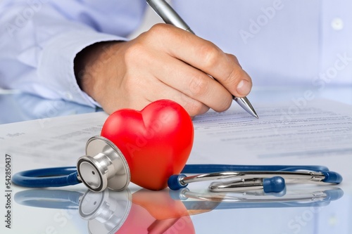 Doctor writing and medical stethoscope on the desk