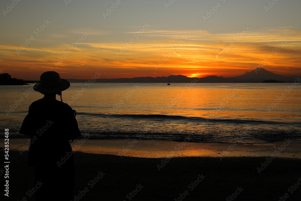 秋の夕暮れの逗子海岸でたたずむ女性のシルエット