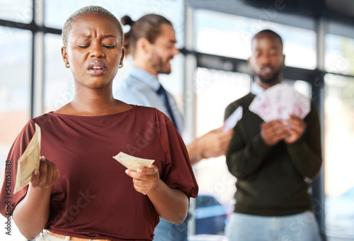 Black woman, unequal pay and confused by wages, paycheck and quote in office, frustrated and annoyed. Angry, woman and reading salary slip with happy colleagues in background, unfair and compensation photo