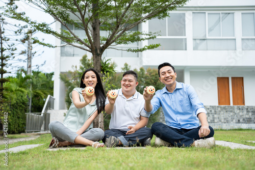 Asian young parents and young son with down syndrome playing in garden