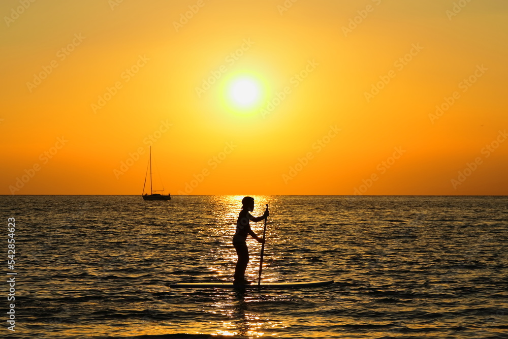 夕暮れの逗子海岸、オレンジに染まる海でSUPを楽しむ若者