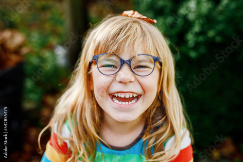 Fall portrait of little preschool girl in autumn park on warm october day with oak and maple leaf. Child with lot of leaves. Family outdoor fun in fall. Kid smiling. Healthy funny child with glasses