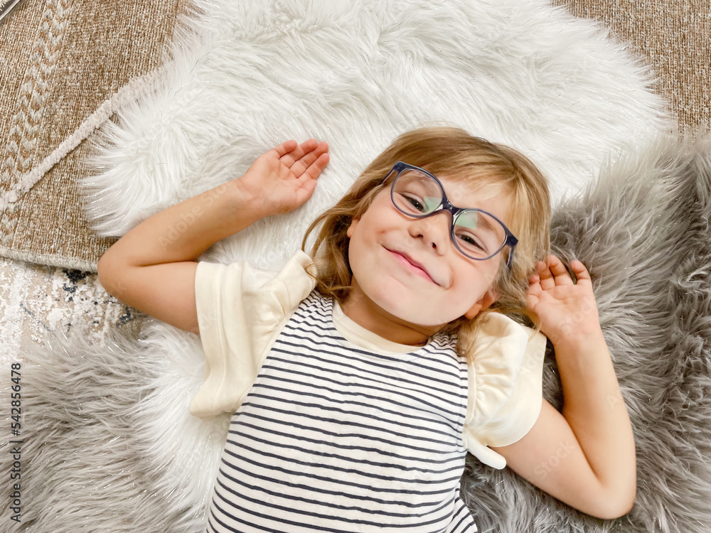 Portrait of a cute preschool girl with eye glasses indoors. Happy funny child wearing new blue glasses. Portrait of a cute preschool girl with eye glasses indoors. Happy funny child wearing new blue glasses.