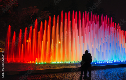 People looking at an impressive and colorful fountain in the Magic water circuit at Reserve park, Lima, Peru