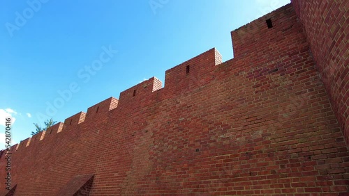 Old Brick Wall Structure Of Warsaw Barbican Against Blue Sky. Historical Landmark In Warsaw, Poland. low angle, pan left photo