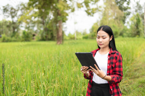 young asian agronomist farmer smiling and holding mobile smart tablet