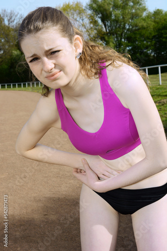 Sporty teenage girl has side-paws and pain from running and jogging 