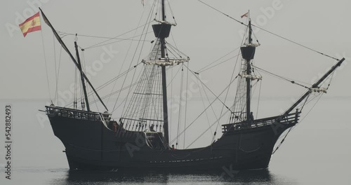 Ferdinand Magellan Nao Victoria carrack boat replica with spanish flag sails in the mediterranean at sunrise in calm sea side shot in slow motion 60fps photo