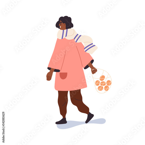 Black woman going outdoors in winter. Happy girl walking in street, carrying ...
