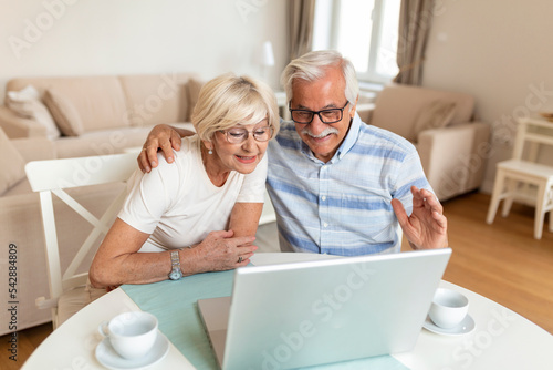 Senior couple is talking online via video connection on the laptop. Having nice time withfriends and family via video call. photo