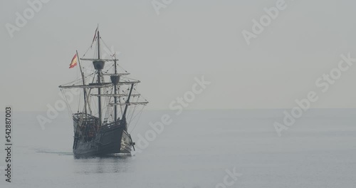Ferdinand Magellan Nao Victoria carrack boat replica with spanish flag sails in the mediterranean at sunrise in calm sea front shot in slow motion 60fps photo