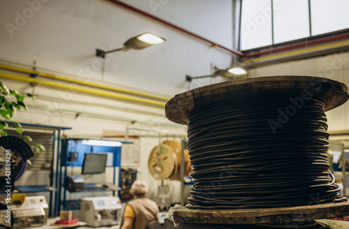 Large wooden cable pulleys with electric cables. Cable reels, cable drums lying on the construction site. In the background, the blue sky and mountains covered with green vegetation photo