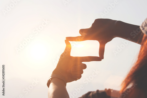 Fotografía Planning and vision concept of new year's start, woman hands making frame gesture find focus at sunset, woman looking for perspective to capture the meaning of a clear upcoming target