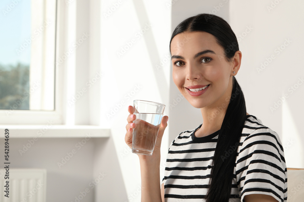 Young woman with glass of water indoors, space for text. Refreshing drink Young woman with glass of water indoors, space for text. Refreshing drink