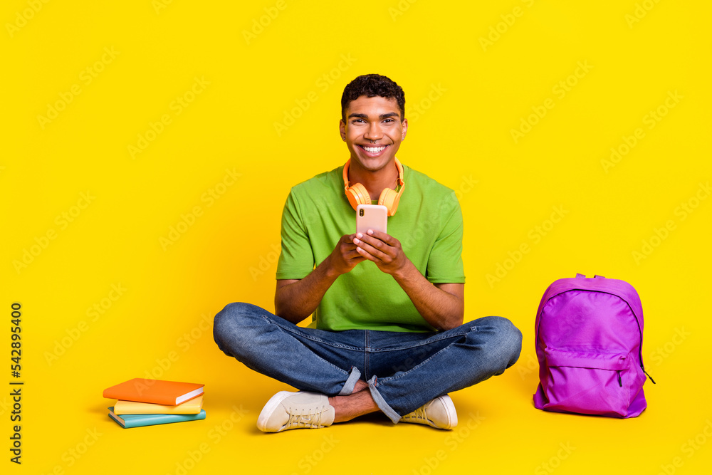 Full length photo of cute cheerful guy wear green t-shirt chatting twitter facebook telegram isolated yellow color background Full length photo of cute cheerful guy wear green t-shirt chatting twitter facebook telegram isolated yellow color background