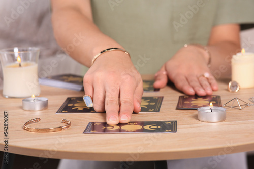 Soothsayer predicting future with tarot cards at table indoors, closeup