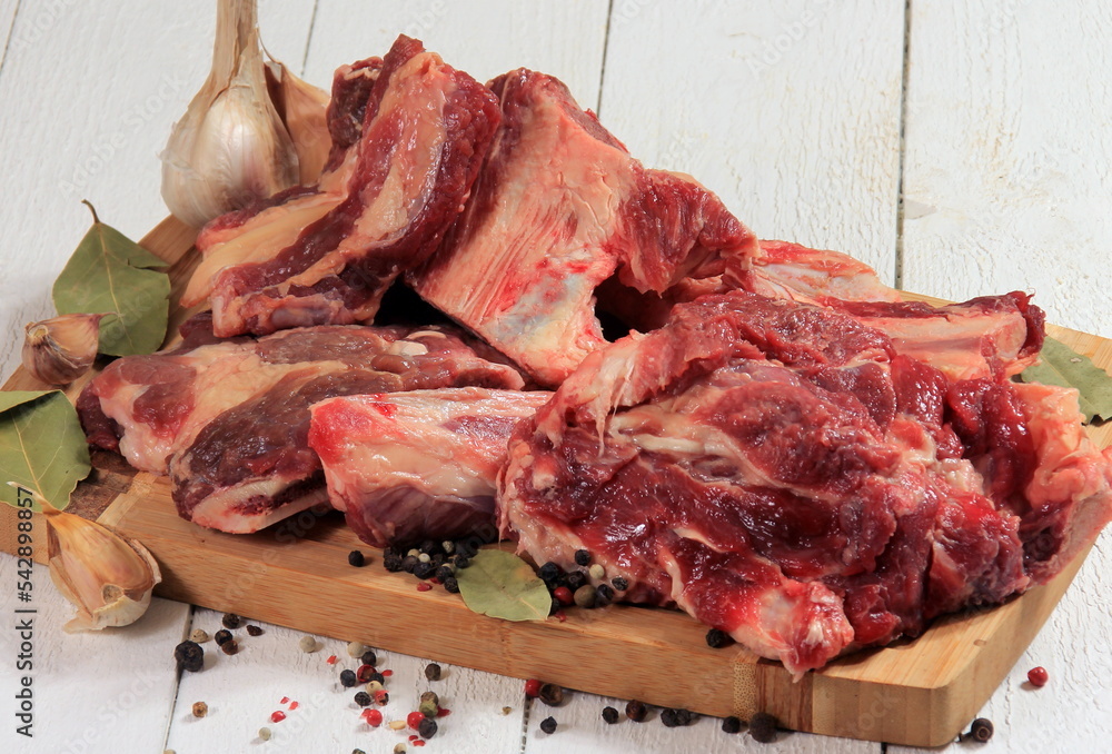 Beef bone selection for soup. Fresh pieces of meat with bones with spices, parsley and bay leaves on a white background