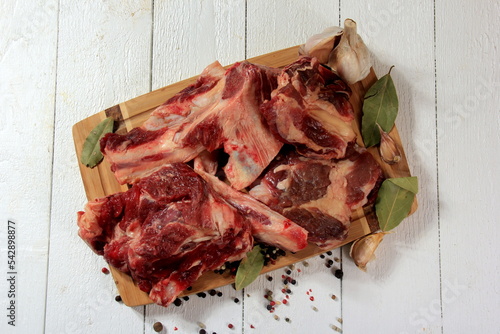 Beef bone selection for soup. Fresh pieces of meat with bones with spices, parsley and bay leaves on a white background photo