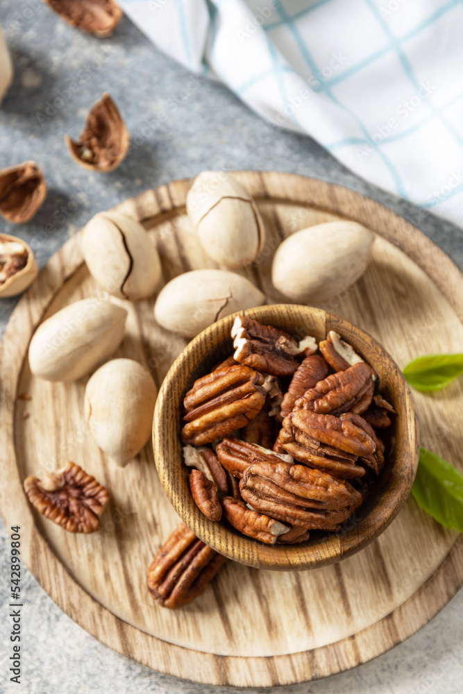 Bowl with pecan nuts on a stone table. Nuts and seeds, healthy fats, various trace elements and vitamins. Bowl with pecan nuts on a stone table. Nuts and seeds, healthy fats, various trace elements and vitamins.