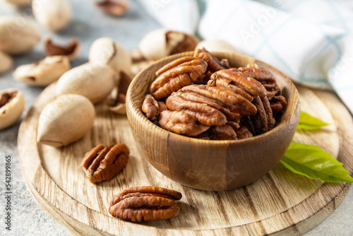 Nuts and seeds, healthy fats, various trace elements and vitamins. Bowl with pecan nuts on a stone table. photo