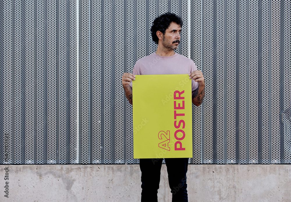 Man Holding A2 Poster Mockup in front a Metallic Wall Stock-Vorlage | Adobe  Stock