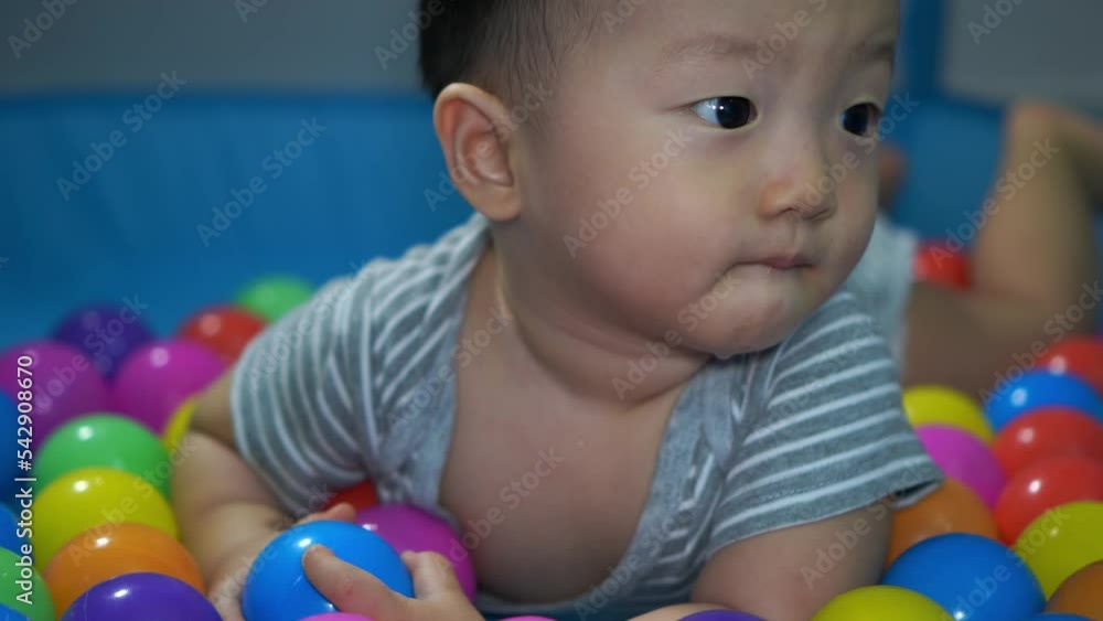 Little kid smile in ball playpen. Babyhood, home concept Little kid smile in ball playpen. Babyhood, home concept
