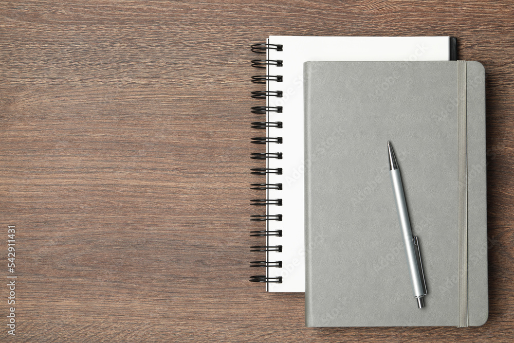 Stylish notebooks and pen on wooden table, top view. Space for text Stylish notebooks and pen on wooden table, top view. Space for text