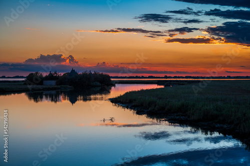 Fototapeta Naklejka Na Ścianę i Meble -  Towards the sunset. Marano lagoon late summer colors. Clouds and sun