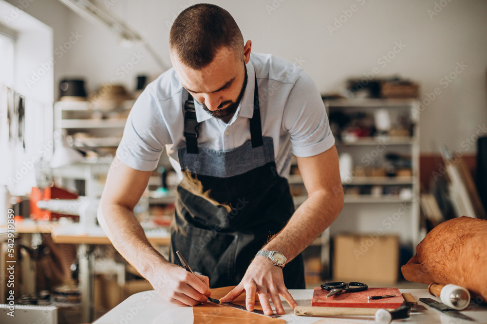 Male designer and leather tailor working at a factory Male designer and leather tailor working at a factory