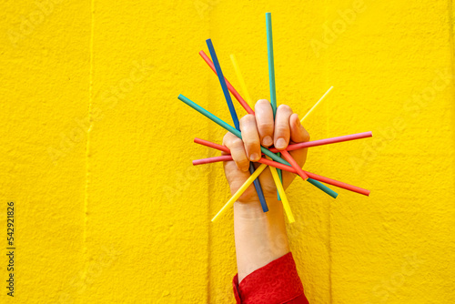 Hand of woman holding colored pencils in front of yellow wall photo