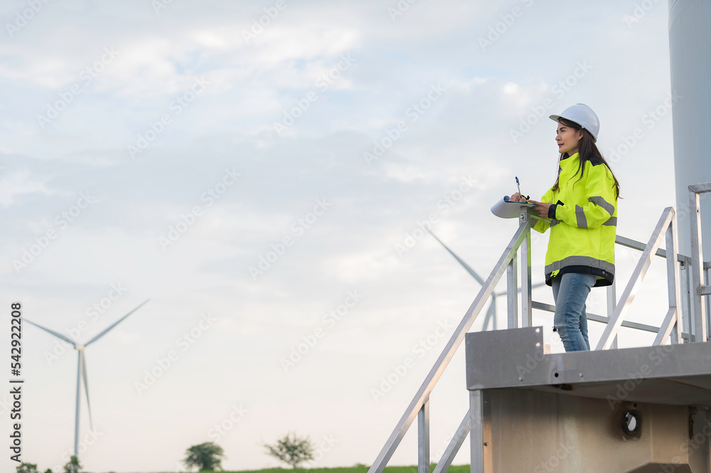 Engineers working and holding the report at wind turbine farm Power Generator Station on mountain,Thailand people,Technician man and woman discuss about work.,Use drone view from high angle Engineers working and holding the report at wind turbine farm Power Generator Station on mountain,Thailand people,Technician man and woman discuss about work.,Use drone view from high angle