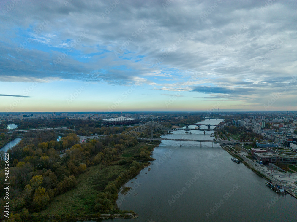 panorama warszawy z rzeką Wisłą i mostami w pochmurny dzień o zachodzie słońca, jesień
