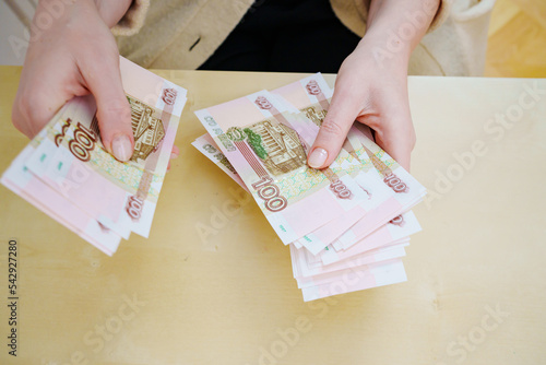 a woman holds in her hands and recalculates Russian banknotes of 100 rubles.  photo