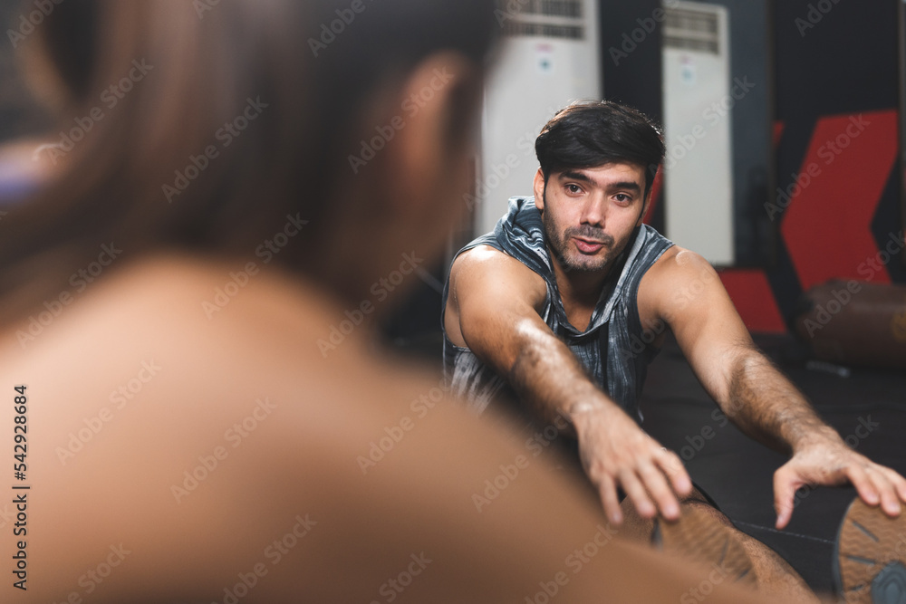Happy and smiling young group of male and female friends in sportswear clothing working out in plank pose together while on modern gym and fitness club on floor and talking to each other