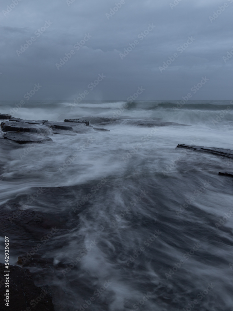 Wave water flowing between rocks on the shore. Wave water flowing between rocks on the shore.