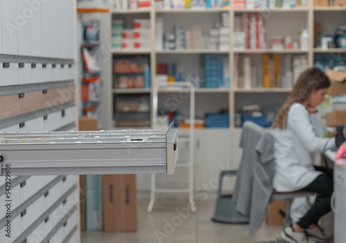 Farmacéutica haciendo un pedido de medicamentos, en el almacén con cajoneras. photo