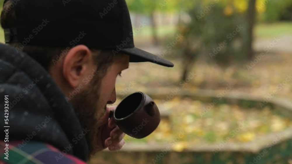 close-up. bearded guy sniffs tea from a clay teapot before drinking it. outdoor tea ceremony close-up. bearded guy sniffs tea from a clay teapot before drinking it. outdoor tea ceremony