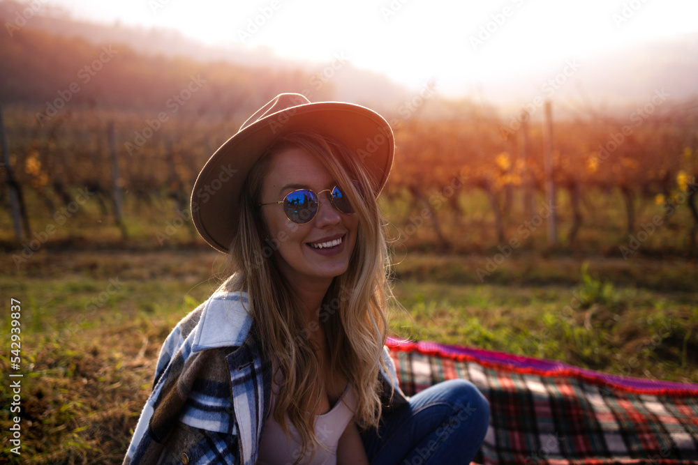 Portrait of smiling woman drinking red wine at vineyard during the sunset.  woman tasting some red wine in a vineyard on a summer afternoon. She's smelling the wine with 