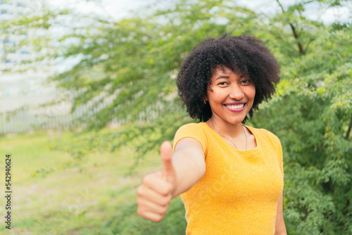 Portrait Afro woman looking at the camera while posing on a natural green background.