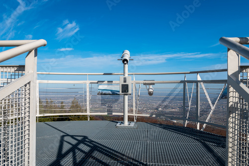 Viewing platform with telescope on Szyndzielnia Mountain in Bielsko-Biala, Poland. Railing and protection of observation tower deck. Peak of thees and cityscape in the background. Blurred horizon. photo