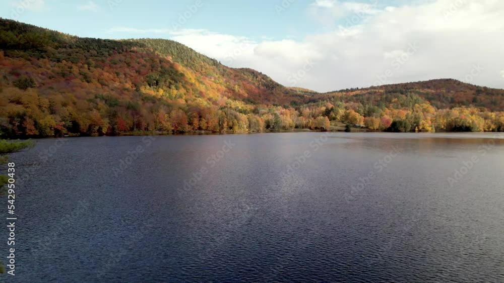 aerial push in to fall color over lake in fall in vermont