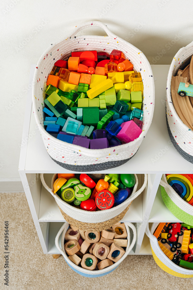 Colorful storage baskets on shelves. White shelving with rainbow wooden