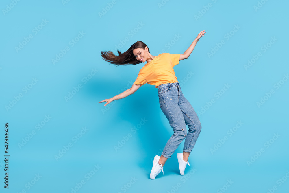Full length photo of adorable pretty lady wear yellow t-shirt dancing having fun empty space isolated blue color background Full length photo of adorable pretty lady wear yellow t-shirt dancing having fun empty space isolated blue color background