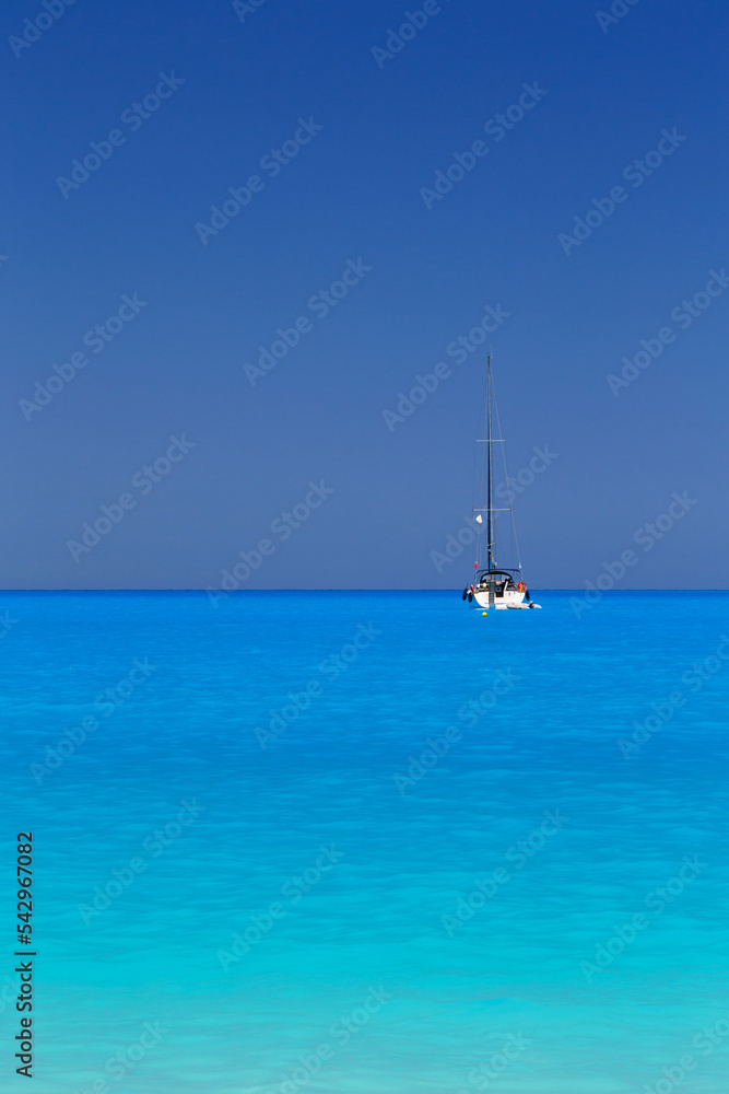 White yacht anchored in fantastic Myrtos Beach turquoise and blue bay. Summer scenery of famous and extremely popular travel destination in Cephalonia island, Greece, Europe.